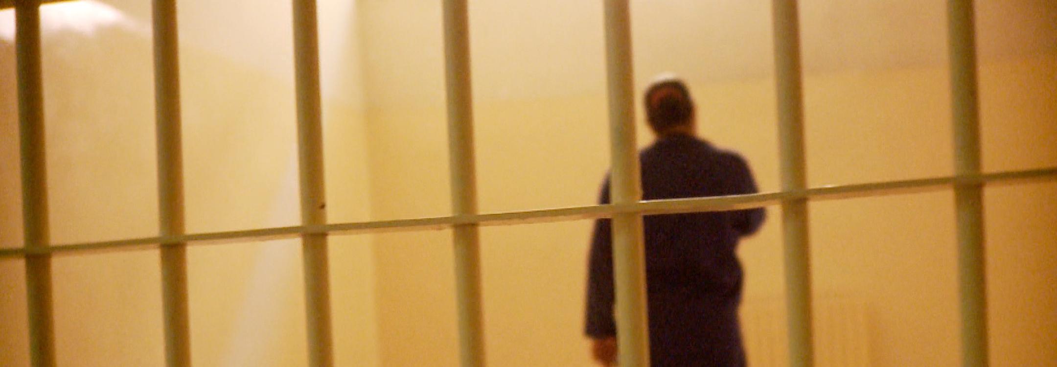 A woman stands alone in a cell